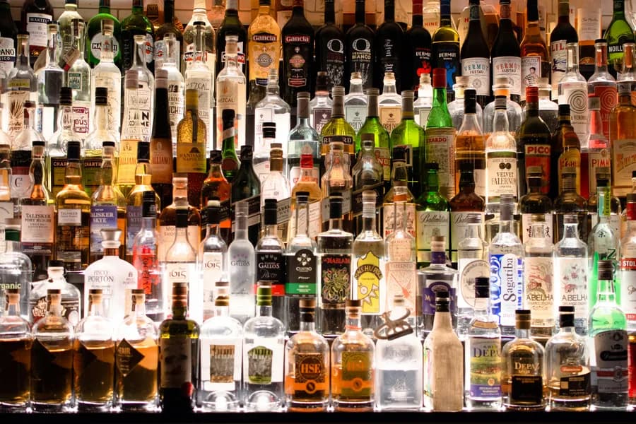 A huge backlit wall of liquor bottles behind a bar