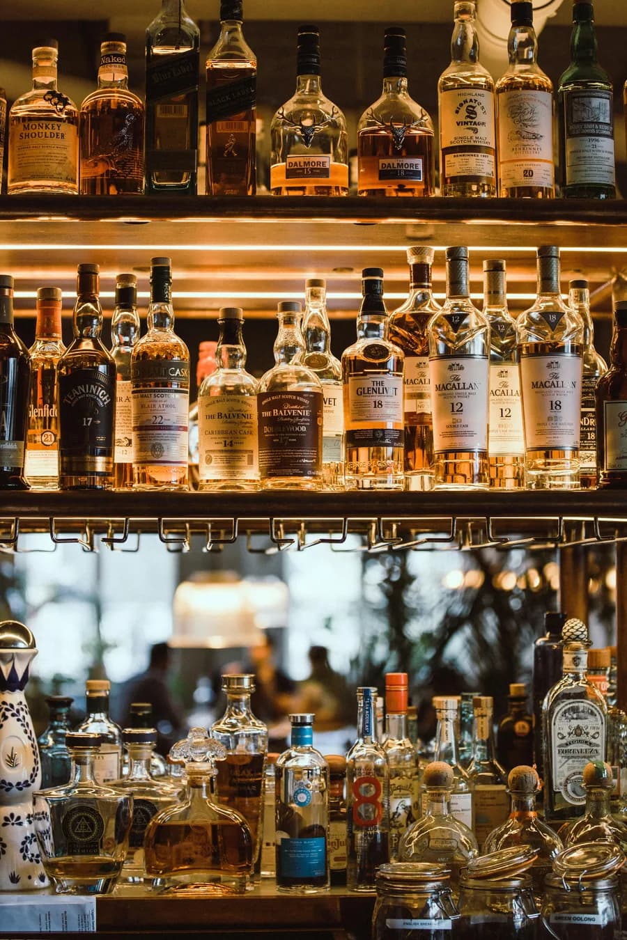 A backlit wall of premium whisky bottles at a bar