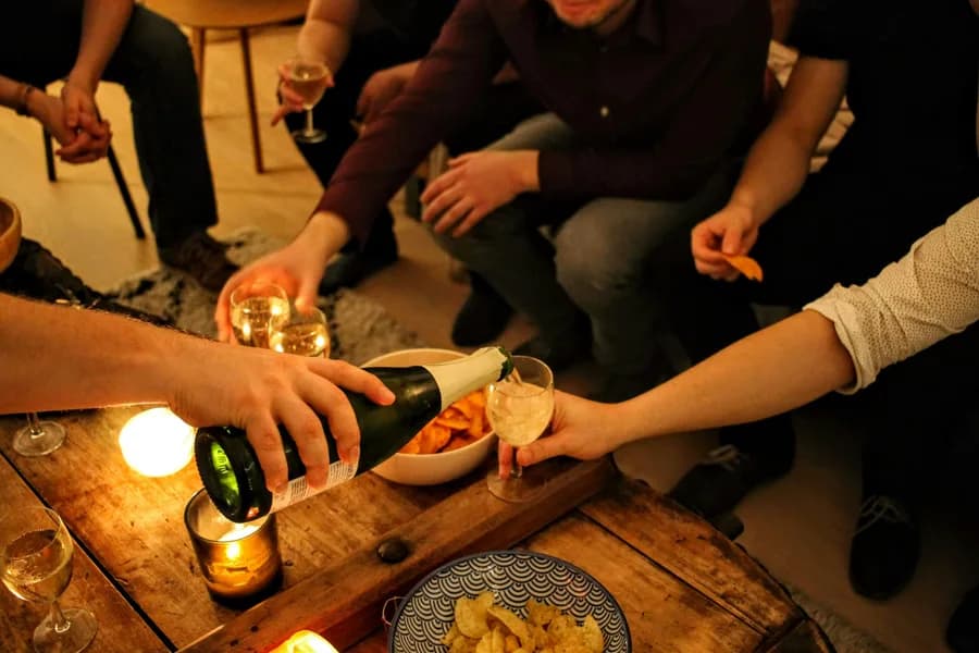 Friends gathered around pouring wine and laughing