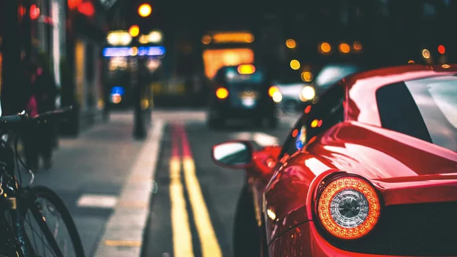 A red sports car moving through a city street at night with bokeh lights