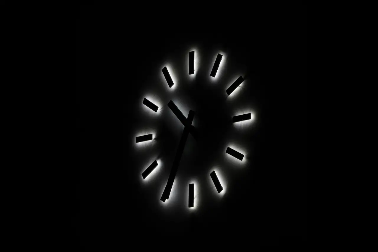 A glowing clock face against a pitch black background