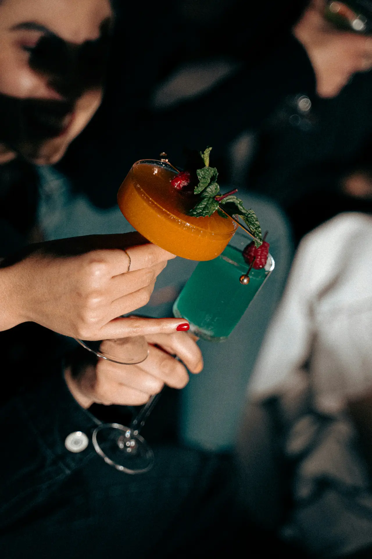 An elaborate layered cocktail held by hand in a nightclub setting