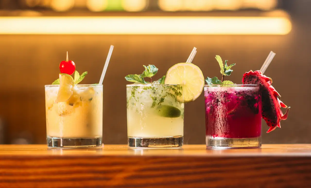 Three colorful cocktails on a bar
