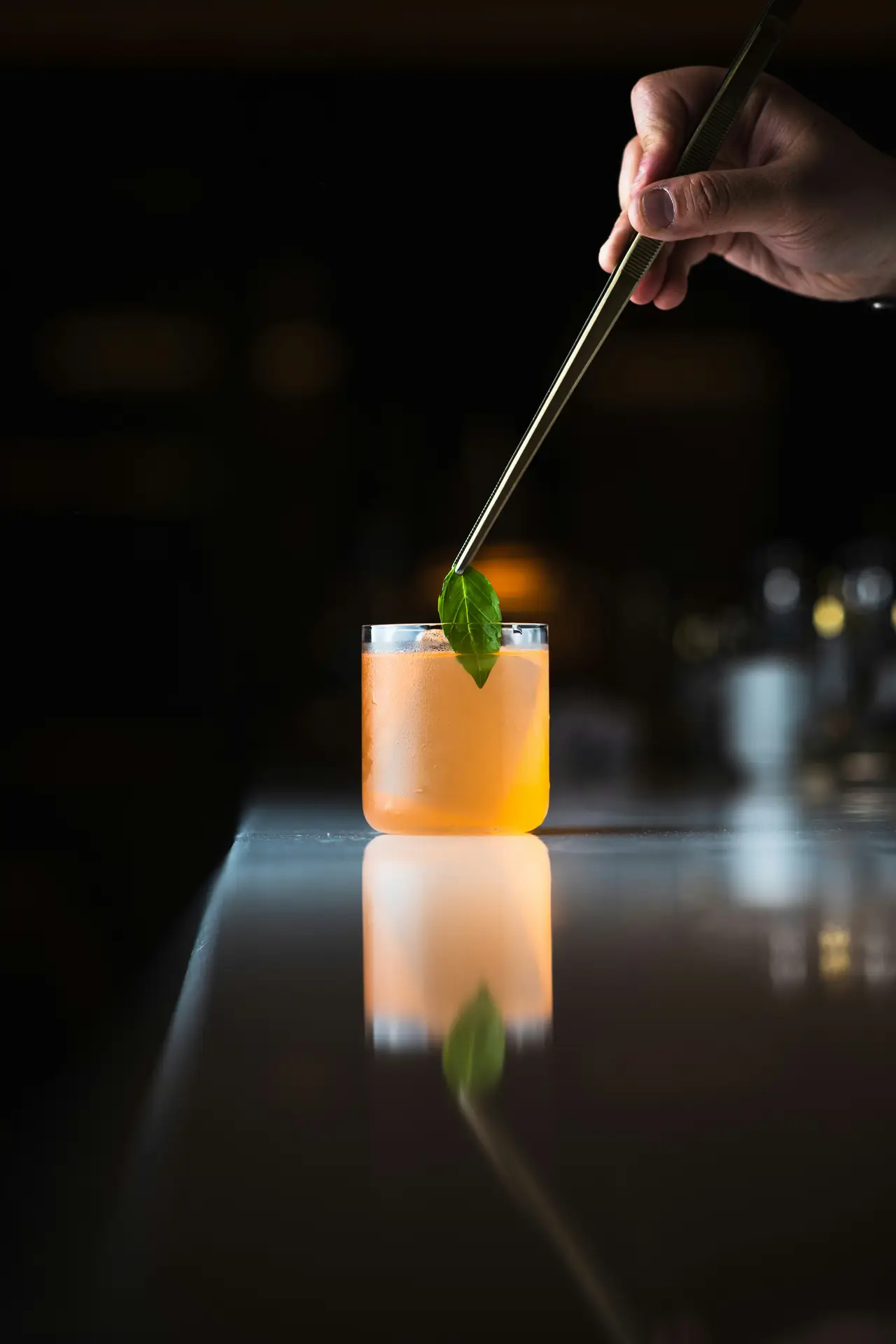 A craft cocktail being garnished on a dark bar